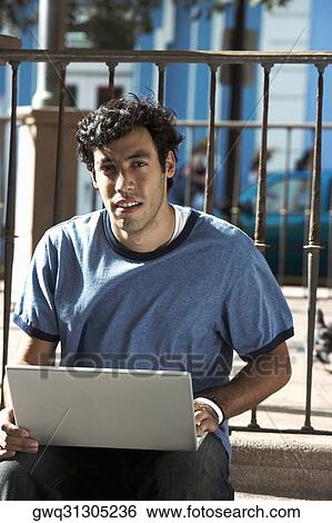 Portrait of a young man using a laptop View Large Photo Image Stock Photograph - Portrait of a young man using a laptop. Fotosearch