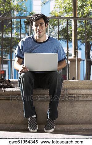 Portrait of a young man using a laptop View Large Photo Image Stock Photography - Portrait of a young man using a laptop. Fotosearch