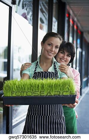 Portrait of a young woman and her mother standing with a tray of wheatgrass and smiling View Large Photo Image Stock Photography - Portrait of a young woman and her mother standing with a tray of wheatgrass and smiling. Fotosearch