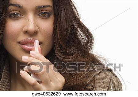 Portrait of a young woman applying lip gloss View Large Photo Image Stock Photo - Portrait of a young woman applying lip gloss. Fotosearch