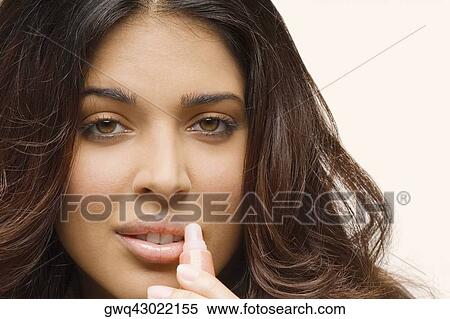 Stock Photography - Portrait of a young woman applying lip gloss. Fotosearch