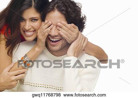 Portrait of a young woman covering eyes of a young man from behind View Large Photo Image Stock Photo - Portrait of a young woman covering eyes of a young man from behind. Fotosearch
