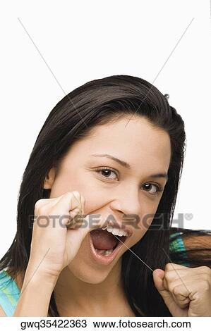 Stock Image - Portrait of a young woman flossing her teeth. Fotosearch