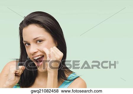 Stock Photo - Portrait of a young woman flossing her teeth. Fotosearch