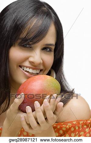 Portrait of a young woman holding a mango and smiling View Large Photo Image Stock Image - Portrait of a young woman holding a mango and smiling. Fotosearch