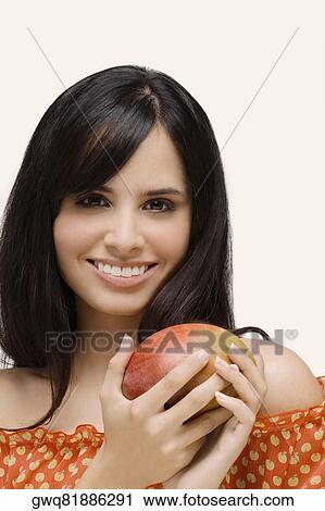 Portrait of a young woman holding a mango and smiling View Large Photo Image Stock Image - Portrait of a young woman holding a mango and smiling. Fotosearch