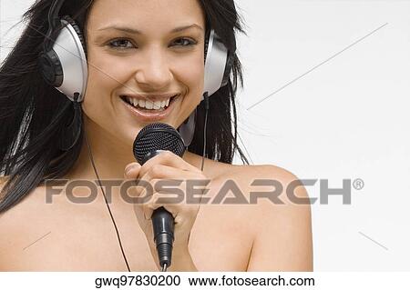 Stock Image - Portrait of a young woman holding a microphone and smiling. Fotosearch
