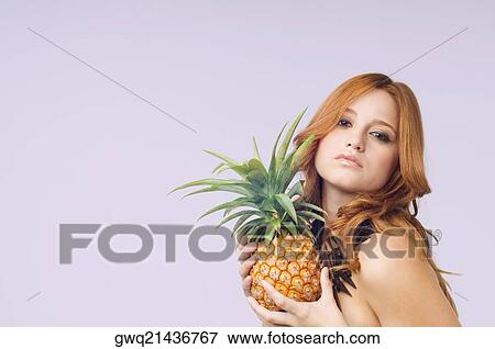 Stock Photo - Portrait of a young woman holding a pineapple. Fotosearch