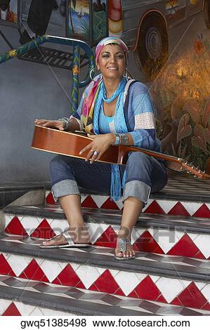 Portrait of a young woman holding a guitar View Large Photo Image Stock Photo - Portrait of a young woman holding a guitar. Fotosearch