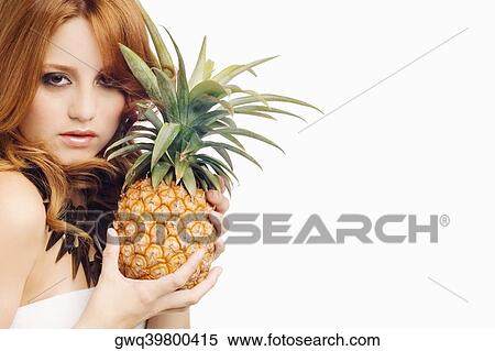 Stock Photography - Portrait of a young woman holding a pineapple. Fotosearch