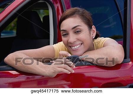 Portrait of a young woman leaning on the window of a car and showing a car key View Large Photo Image Stock Photography - Portrait of a young woman leaning on the window of a car and showing a car key. Fotosearch