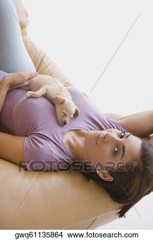 Portrait of a young woman lying on a couch with a puppy on her View Large Photo Image Picture - Portrait of a young woman lying on a couch with a puppy on her. Fotosearch