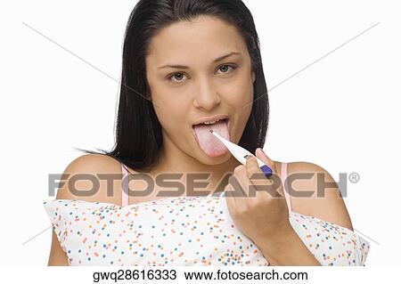 Portrait of a young woman measuring her temperature with a digital thermometer View Large Photo Image Stock Image - Portrait of a young woman measuring her temperature with a digital thermometer. Fotosearch