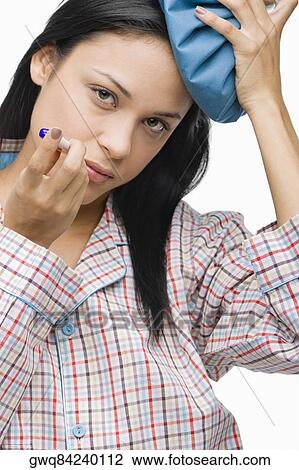 Portrait of a young woman measuring her temperature with a thermometer and holding an ice pack on her head View Large Photo Image Stock Image - Portrait of a young woman measuring her temperature with a thermometer and holding an ice pack on her head. Fotosearch