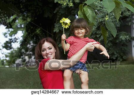 Portrait of a young woman picking up her daughter and smiling View Large Photo Image Stock Photo - Portrait of a young woman picking up her daughter and smiling. Fotosearch