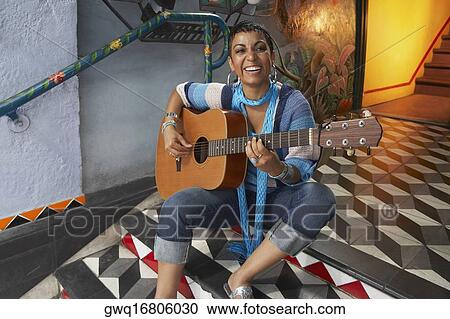 Portrait of a young woman playing a guitar View Large Photo Image Stock Image - Portrait of a young woman playing a guitar. Fotosearch