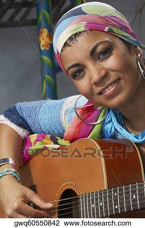 Stock Image - Portrait of a young woman playing a guitar. Fotosearch