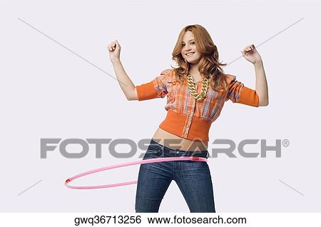 Portrait of a young woman playing with a hula hoop View Large Photo Image Stock Photograph - Portrait of a young woman playing with a hula hoop. Fotosearch
