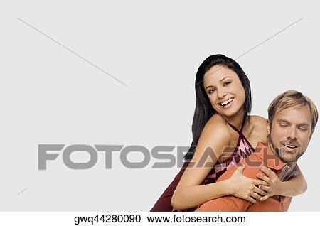 Stock Image - Portrait of a young woman riding piggyback on a mid adult man. Fotosearch