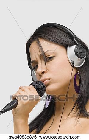 Portrait of a young woman singing into a microphone View Large Photo Image Stock Photograph - Portrait of a young woman singing into a microphone. Fotosearch