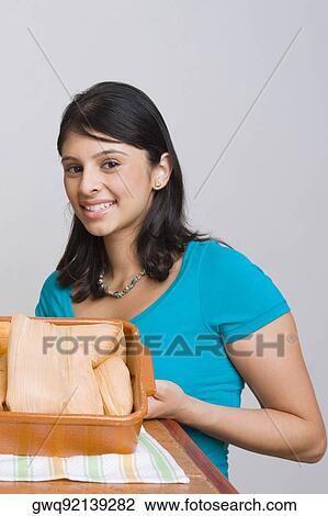 Portrait of a young woman smiling with a tray of breads in the kitchen View Large Photo Image Stock Image - Portrait of a young woman smiling with a tray of breads in the kitchen. Fotosearch