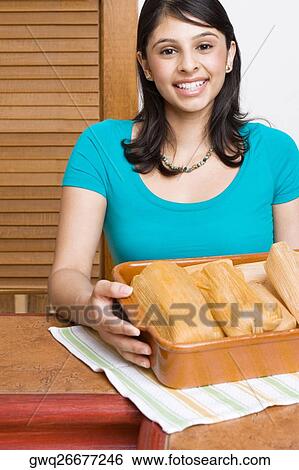 Portrait of a young woman smiling with a tray of breads in the kitchen View Large Photo Image Stock Photograph - Portrait of a young woman smiling with a tray of breads in the kitchen. Fotosearch