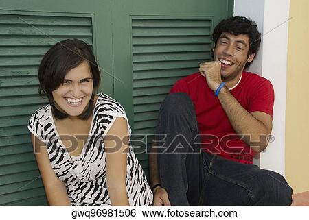 Portrait of a young woman smiling with a young man sitting beside her and coughing View Large Photo Image Stock Photograph - Portrait of a young woman smiling with a young man sitting beside her and coughing. Fotosearch