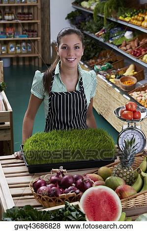 Portrait of a young woman standing in a grocery store and smiling View Large Photo Image Stock Photo - Portrait of a young woman standing in a grocery store and smiling. Fotosearch