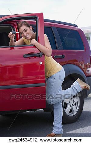 Portrait of a young woman standing near the open door of a car and showing a car key View Large Photo Image Stock Image - Portrait of a young woman standing near the open door of a car and showing a car key. Fotosearch