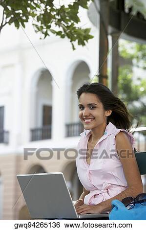 Stock Photograph - Portrait of a young woman using a laptop and smiling, Old San Juan, San Juan, Puerto Rico. Fotosearch