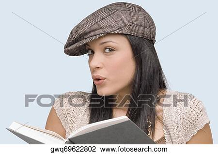 Stock Image - Portrait of a young woman whistling with a book in front of her. Fotosearch