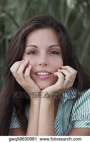 Portrait of a young woman with her hands on her chin View Large Photo Image Stock Image - Portrait of a young woman with her hands on her chin. Fotosearch