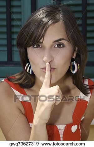 Portrait of a young woman with her finger on her lips View Large Photo Image Stock Photo - Portrait of a young woman with her finger on her lips. Fotosearch