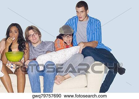 Stock Image - Portrait of four friends sitting on a couch and watching television. Fotosearch