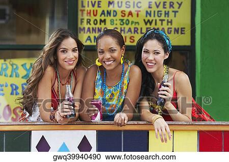 Portrait of three young women leaning on a railing and holding cold drinks View Large Photo Image Stock Image - Portrait of three young women leaning on a railing and holding cold drinks. Fotosearch