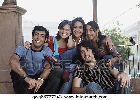 Stock Image - Portrait of three young women smiling with two young men. Fotosearch