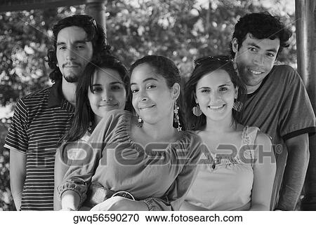 Stock Image - Portrait of three young women standing with their friends. Fotosearch
