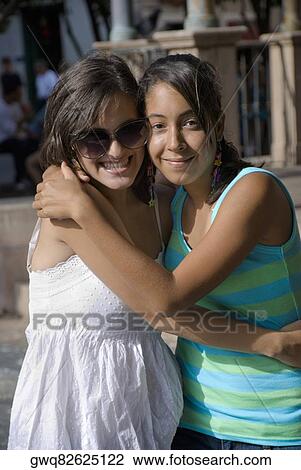 Stock Image - Portrait of two young women smiling and embracing each other. Fotosearch