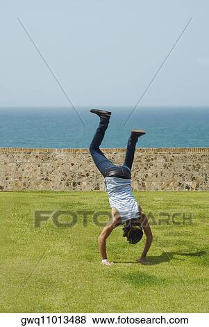 Stock Photo - Rear view of a man doing a handstand in a park. Fotosearch