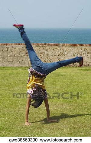 Rear view of a woman doing a handstand in a park View Large Photo Image Stock Image - Rear view of a woman doing a handstand in a park. Fotosearch
