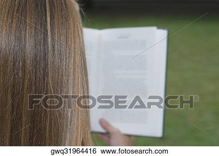 Rear view of a woman reading a book View Large Photo Image Stock Photograph - Rear view of a woman reading a book. Fotosearch