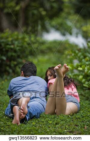 Rear view of a young couple lying in a park View Large Photo Image Stock Image - Rear view of a young couple lying in a park. Fotosearch