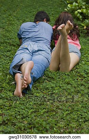 Rear view of a young couple lying in a park View Large Photo Image Stock Photo - Rear view of a young couple lying in a park. Fotosearch