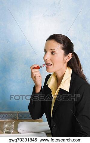 Side profile of a businesswoman applying lipstick on her lips View Large Photo Image Stock Photography - Side profile of a businesswoman applying lipstick on her lips. Fotosearch