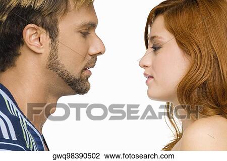 Stock Image - Side profile of a couple looking at each other. Fotosearch