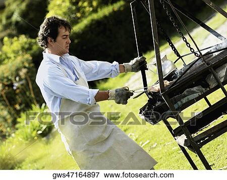 Stock Photo - Side profile of a man cooking on a barbeque grill. Fotosearch