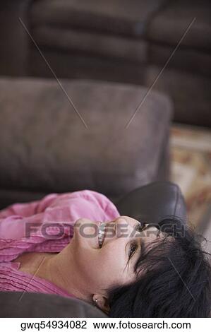 Side profile of a mature woman lying on a couch and smiling View Large Photo Image Stock Image - Side profile of a mature woman lying on a couch and smiling. Fotosearch