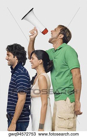 Side profile of a mid adult man shouting into a megaphone behind his friends View Large Photo Image Stock Image - Side profile of a mid adult man shouting into a megaphone behind his friends. Fotosearch