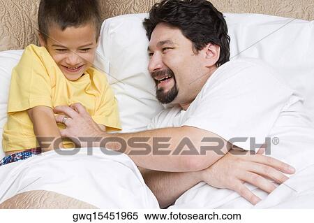 Side profile of a mid adult man tickling his son on the bed View Large Photo Image Stock Photography - Side profile of a mid adult man tickling his son on the bed. Fotosearch