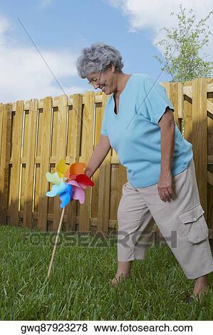 Side profile of a senior woman fixing a pinwheel in a lawn and smiling View Large Photo Image Stock Photo - Side profile of a senior woman fixing a pinwheel in a lawn and smiling. Fotosearch